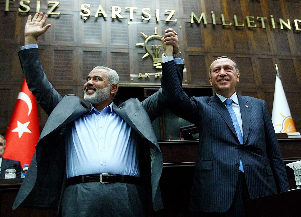 The Gaza Strip's Hamas Prime minister Ismail Haniyeh (L) and his Turkish counterpart Recep Tayyip Erdogan salute together the lawmakers of Erdogan's Islamic-rooted Justice and Development Party at the Parliament in Ankara on January 3, 2012. Haniyeh's visit was a show of solidarity with the Islamic aid group IHH, which had planned to send the Mavi Marmara vessel with another Gaza flotilla last year but then dropped the plan. AFP PHOTO/ADEM ALTAN (Photo credit should read ADEM ALTAN/AFP via Getty Images)