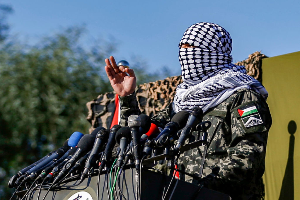 A masked Palestinian militant gives a speech in a press conference during a military drill by Hamas and other Palestinian armed factions on a beach in Gaza City on December 29, 2020. (Photo by MOHAMMED ABED / AFP) (Photo by MOHAMMED ABED/AFP via Getty Images)