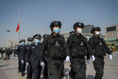 BEIJING, CHINA - APRIL 04: Chinese police officers wear protective masks as they march in formation away from a national flag at half staff after observing three minutes of silence to mark the country's national day of mourning for COVID-19 at Beijing Railway Station on April 4, 2020 in Beijing, China. Across the country people paused, and sirens and horns wailed for three minutes to remember medical personnel and patients who died during the coronavirus outbreak. With the pandemic hitting hard across the world, officially the number of coronavirus cases in China is dwindling, since the government imposed sweeping measures to keep the disease from spreading. For two months, millions of people across China have been restricted in how they move from their homes, while other cities have been locked down in ways that appeared severe at the time but are now being replicated in other countries trying to contain the virus. Officials believe the worst appears to be over in China, though there are concerns of another wave of infections as the government attempts to reboot the worlds second largest economy. In Beijing, it is mandatory to wear masks outdoors, retail stores operate on reduced hours, restaurants employ social distancing among patrons, and tourist attractions at risk of drawing large crowds remain closed. Monitoring and enforcement of virus-related measures and the quarantine of anyone arriving to Beijing is carried out by neighborhood committees and a network of Communist Party volunteers who wear red arm bands. A primary concern for Chinese authorities remains the arrival of flights from Europe and elsewhere, given the exposure of passengers in regions now regarded as hotbeds for transmission. Since January, China has recorded more than 81,000 cases of COVID-19 and at least 3200 deaths, mostly in and around the city of Wuhan, in central Hubei province, where the outbreak first started. (Photo by Kevin Frayer/Getty Images)