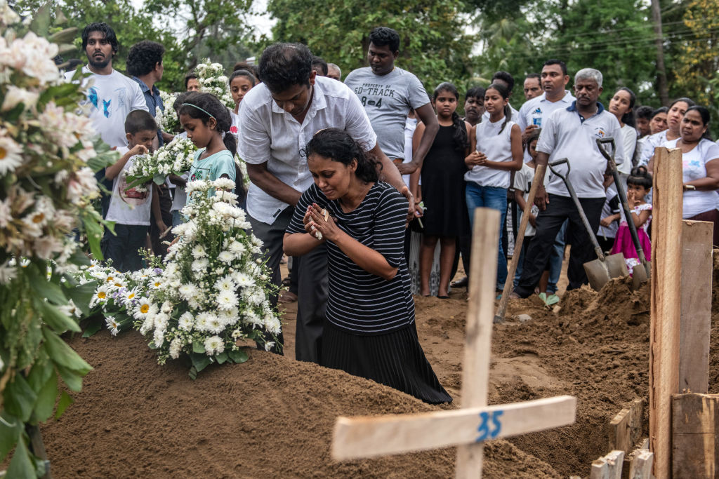 NEGOMBO, SRI LANKA - APRIL 25: A woman grieves at the grave after a funeral for a person killed in the Easter Sunday attack on St Sebastian's Church, on April 25, 2019 in Negombo, Sri Lanka. At least 359 people were killed and 500 people injured after coordinated attacks on churches and hotels on Easter Sunday which rocked three churches and three luxury hotels in and around Colombo as well as at Batticaloa in Sri Lanka. According to reports, police have identified eight out of nine attackers on Wednesday as the Islamic State group have claimed responsibility for the attacks. Police have detained 60 suspects so far in connection with the suicide bombs while the country's government blame the attacks on local Islamist group National Thowheed Jamath (NTJ). (Photo by Carl Court/Getty Images)