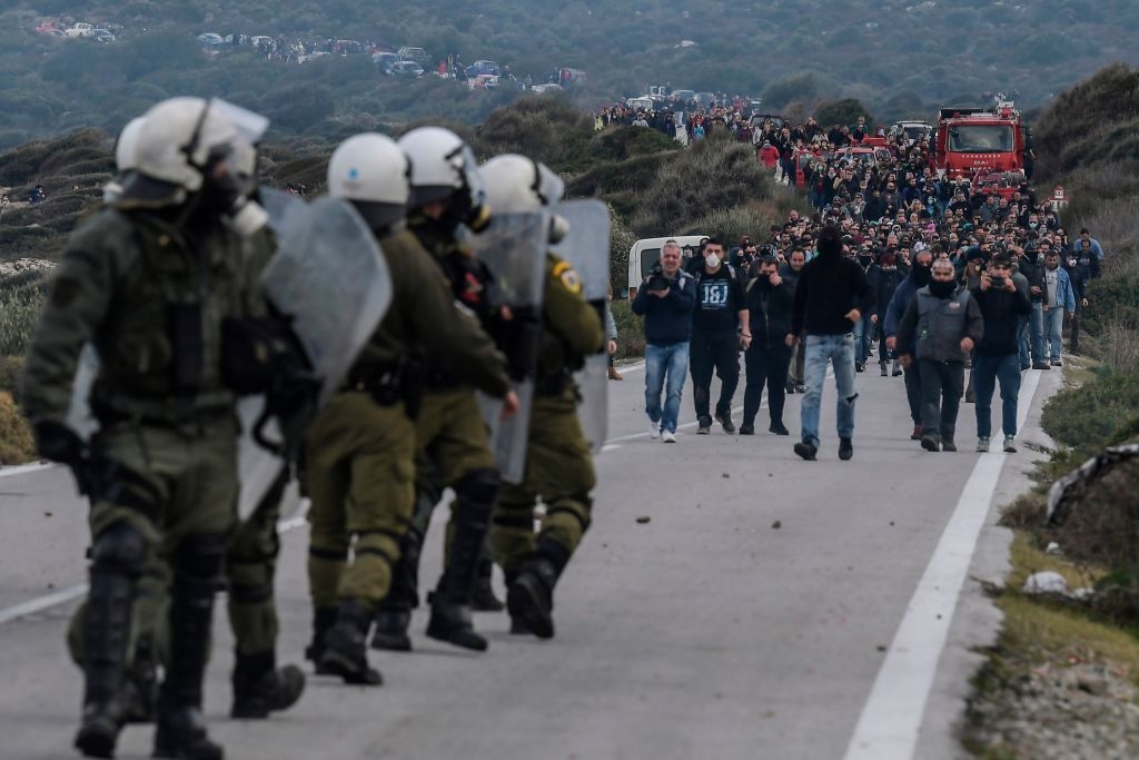 Greek riot police face demonstrators during protests against the construction of a new controversial migrant camp near the town of Mantamados on the northeastern Aegean island of Lesbos, on February 26, 2020. - The Greek islands of Lesbos, Chios and Samos staged a general strike on February 26, as protests against the construction of new migrant camps intensified. For a second day, protesters on Lesbos faced off against riot police near the town of Mantamados, close to the site of a planned camp for up to 7,000 people. Small groups of protesters threw stones and firebombs at the police, who responded with tear gas and flash grenades. (Photo by ARIS MESSINIS / AFP) (Photo by ARIS MESSINIS/AFP via Getty Images)