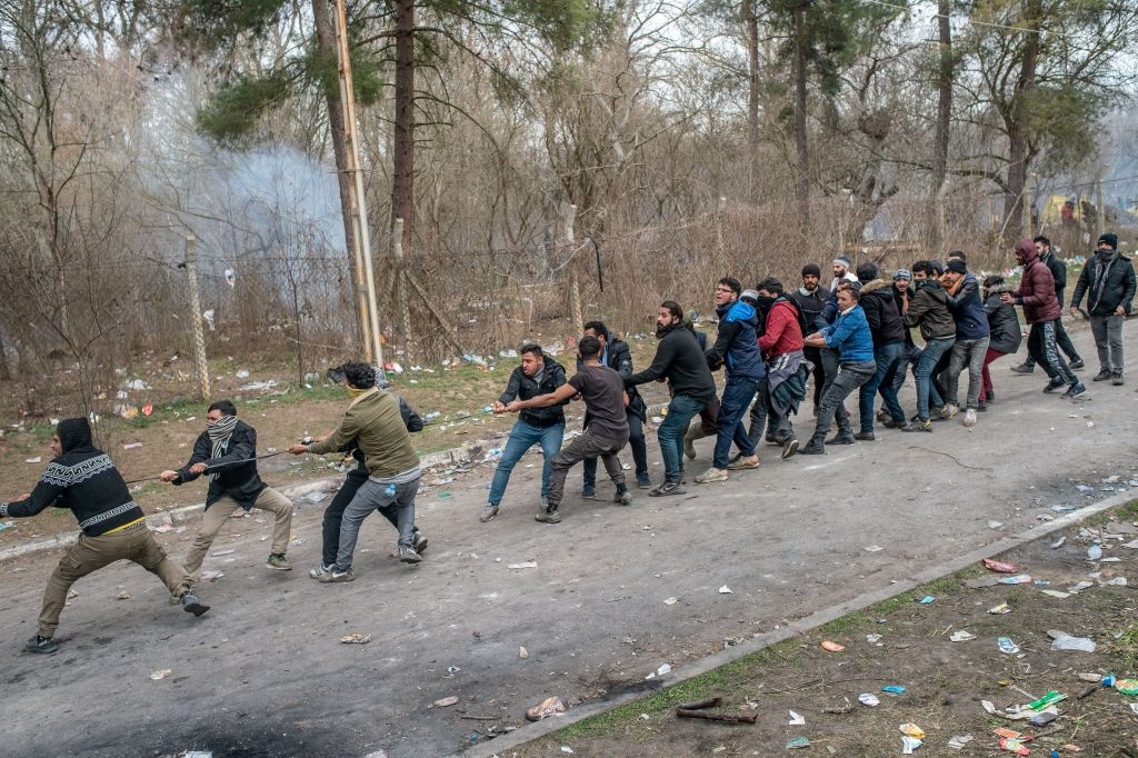 Migrants try to remove fences during the clashes with Greek police, after they tried to pass on Greek side, on the buffer zone Turkey-Greece border, near Pazarkule crossing gate in Edirne, Turkey,  on March 4, 2020. - Turkish officials claimed on March 4, 2020 that one migrant was killed by Greek fire on the Turkey-Greece border where thousands of migrants have massed since last week. But on the other side Greece "categorically" denied claims by Turkey that it had fired live bullets against migrants on the border, with several allegedly injured and one later dying. (Photo by BULENT KILIC / AFP) (Photo by BULENT KILIC/AFP via Getty Images)